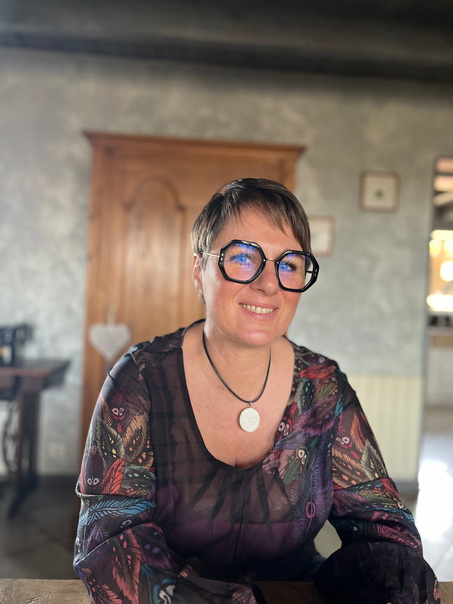 Portrait de Virginie Darme, souriante, avec ses grandes lunettes noires